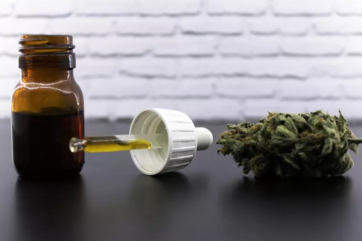 Frasco de CBD y cogollo de marihuana