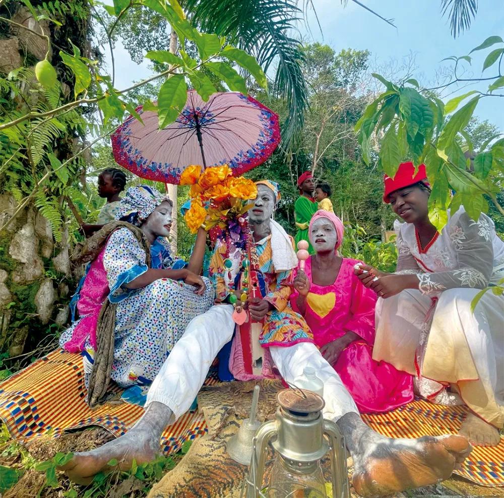 Un grupo de músicos y cantantes tocando bajo los árboles de iboga.